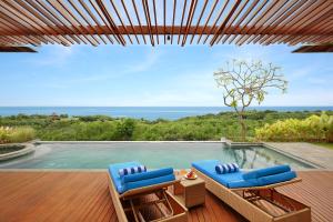 a patio with two blue chairs and a swimming pool at Ocean View Villa Hotman Paris VII in Jimbaran
