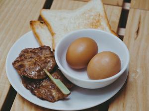 a plate of food with eggs and bread on a table at Mimi and Jim Co-living space in Cha Am