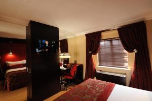 um quarto de hotel com um quarto com uma cama e uma televisão em Cycad Guest House em Polokwane