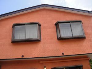 twee ramen aan de zijkant van een rood gebouw bij Turtle Inn Nikko in Nikko