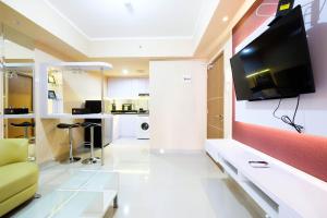 un salon avec une télévision à écran plat sur un mur dans l'établissement Bright and Stylish 1BR The Oasis Apartment Cikarang By Travelio, à Cikarang
