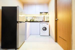 une cuisine avec un réfrigérateur et une machine à laver dans l'établissement Bright and Stylish 1BR The Oasis Apartment Cikarang By Travelio, à Cikarang