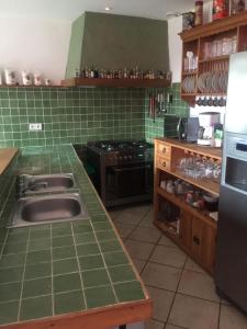 cocina de azulejos verdes con fregadero y fogones en La Forge, en Saint-Maurice-en-Cotentin