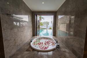 a bathroom with a bath tub with a large window at Villa Maiara in Uluwatu