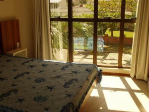 een slaapkamer met een bed voor een raam bij Jurerê - Canto Belo in Florianópolis