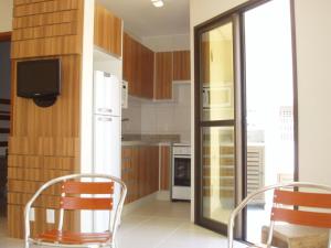 cocina con 2 sillas, mesa y nevera en Jurerê - Canto Belo, en Florianópolis