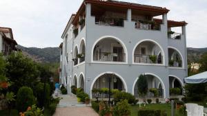 un gran edificio blanco con balcones y plantas en Delphin Rooms Sivota, en Sivota