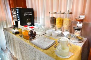 uma mesa com uma toalha amarela com comida e bebidas em Hotel Emma Est em Craiova