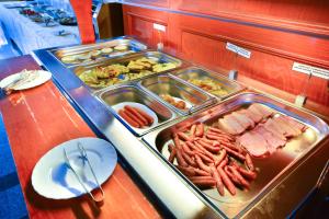 um buffet com muitas bandejas de comida numa mesa em Hotel Emma Est em Craiova