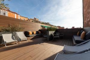 a patio with chairs and couches on a wooden deck at Aspasios Sagrada Familia Apartments in Barcelona