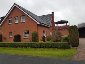 uma casa de tijolos vermelhos com um gazebo em FeWo zwischen den Deichen em Emden