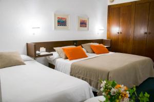 two beds in a hotel room with orange pillows at Hotel America Igualada in Igualada