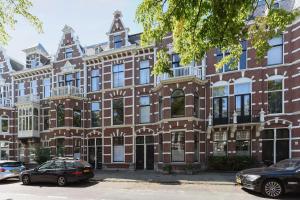 een groot bakstenen gebouw met auto's geparkeerd voor het bij En Suite in Den Haag