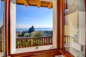 een raam met uitzicht op de oceaan vanuit een huis bij Appartamento Lago Blu in Gardone Riviera