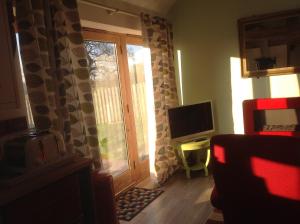 un salon avec une porte et une télévision dans l'établissement ANVIL COTTAGE, à Whitchurch