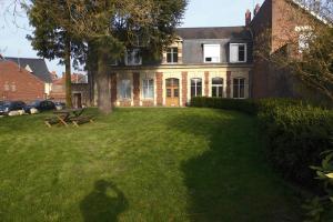 uma casa grande com um relvado verde em frente em Chambres d'Hotes Noir Lion em Péronne
