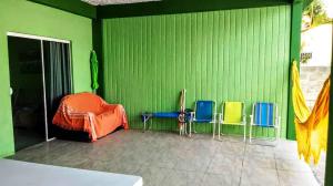 a green room with four chairs and a bed at PONTA DO PAPAGAIO *CASA EM MEIO A DUAS PRAIAS* in Palhoça
