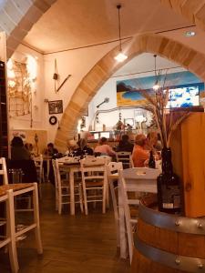 a restaurant with white tables and chairs and a wine bottle at La Praya in Favignana