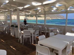 a restaurant with white tables and chairs and the ocean at La Praya in Favignana +21 photos