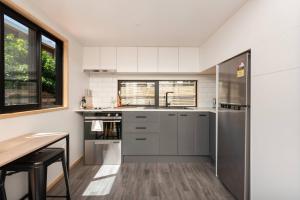 a kitchen with white cabinets and a wooden table at Cozy Tiny House Hideaway in Tauranga