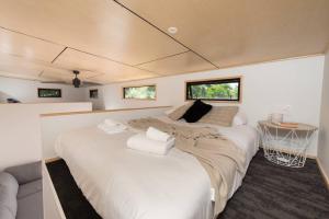 a large white bed in a room with windows at Cozy Tiny House Hideaway in Tauranga