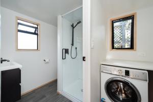 a laundry room with a washing machine and a window at Cozy Tiny House Hideaway in Tauranga