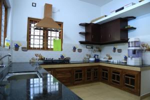 een keuken met houten kasten en een wastafel bij White Clouds Cottage Munnar in Munnar