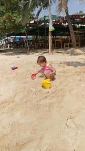 a little girl playing in the sand on the beach at Abani Inn in Jomtien Beach