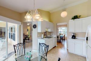 a kitchen with white cabinets and a table and chairs at Marco Sands in Marco Island