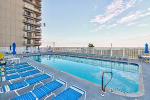 a swimming pool with blue chairs and a building at Sea Terrace Serenity in Ocean City