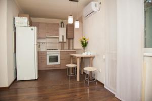 a kitchen with a refrigerator and a table with stools at Semi-luxury Apt on Ukrainskaya 43 Street in Zaporozhye