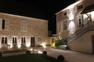 Un grand bâtiment en pierre avec des lumières allumées la nuit dans l'établissement La Maison Deveney Mars, à Puligny-Montrachet