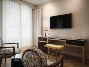 Habitación de hotel con escritorio y TV en la pared en Villa Bavaria en Merano