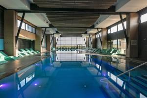 an empty swimming pool with green chairs in a building at Thalazur Cabourg - H&ocirc;tel & Spa in Cabourg