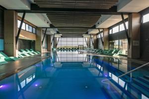 pusty basen z zielonymi krzesłami w budynku w obiekcie Thalazur Cabourg - Hôtel & Spa w mieście Cabourg