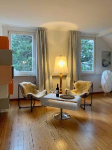 sala de estar con 2 sillas, mesa y 2 ventanas en Deluxe Business City Apartments Metzingen Villa Landenberger, en Metzingen