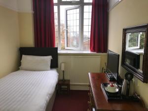 a bedroom with a bed, desk and a television at Barons Court Hotel in Wolverhampton