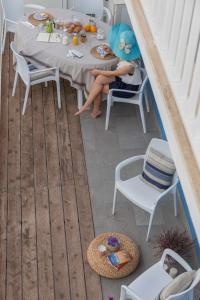 a woman sitting at a table on a patio at Mareinsicilia Cannamara Appartamenti in Donnalucata