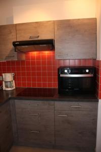 - une cuisine avec un four micro-ondes et du carrelage rouge au mur dans l'établissement Résidence Atlantic, à Coxyde
