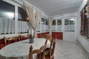 a dining room with a table and chairs and windows at Apartment Lea in Senj