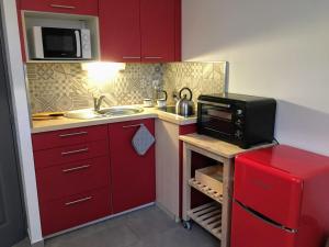 une petite cuisine avec des placards rouges et un four micro-ondes dans l'établissement Gate House Lodge, à Dinan