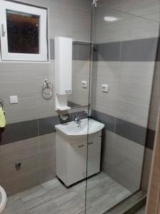 a bathroom with a sink and a glass shower at Apartmani M&V in Sutomore