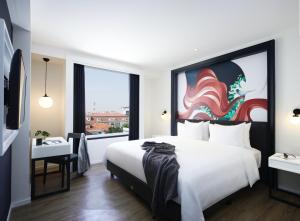 a bedroom with a large white bed and a window at de Braga, ARTOTEL Curated in Bandung