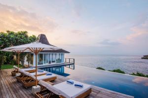 a villa with a pool and a deck with chairs and an umbrella at Villa Tranquilla in Nusa Lembongan
