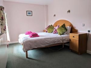 a small bedroom with a bed with green and pink pillows at Mellwaters Barn Cottages in Bowes