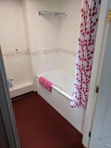 a bathroom with a tub and a pink shower curtain at Mellwaters Barn Cottages in Bowes
