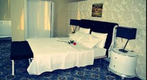 HOTEL DE LA VALLÉE في الشلف: غرفة نوم بسرير ابيض وعليه وردة حمراء