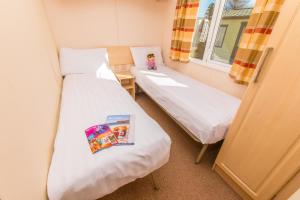 two beds in a small room with a book at Ladram Bay Holiday Park in Otterton