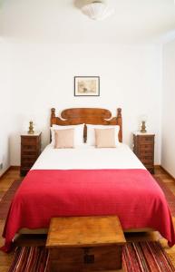 a bedroom with a large bed with a red blanket at Casa da Manta in Fajã da Ovelha