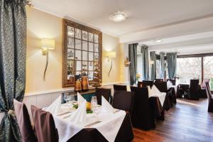 ein Restaurant mit weißen Tischen und schwarzen Stühlen in der Unterkunft Central Hotel am Königshof in Viernheim